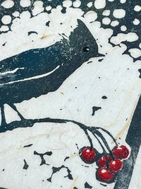 detail shot of block print of songbird on berry branch with snow