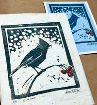 two versions of block print of songbird on berry branch with snow