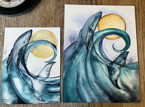 2 watercolor paintings of blue whale arching out of aqua wave with a golden moon