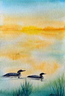 watercolor painting of 2 loons on water with golden light