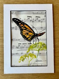 watercolor painting of butterfly and plant on sheet music