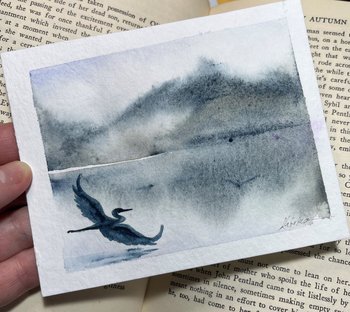 watercolor painting of heron in flight of misty blue grey mountains and water